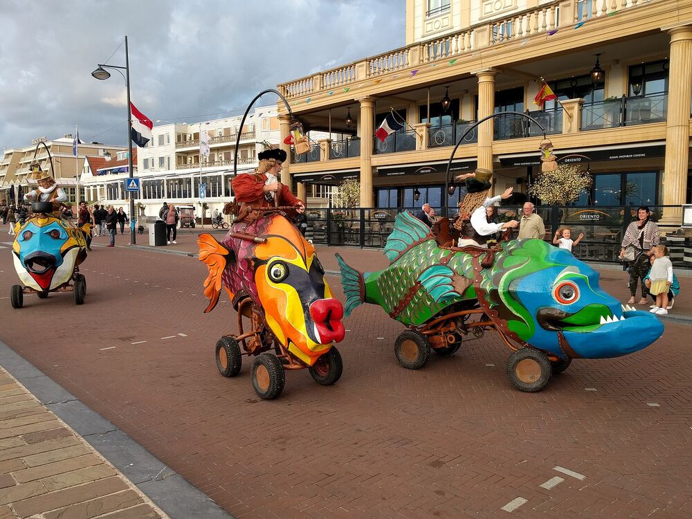 Kinderen en wandelaars op de boulevard van Noordwijk bij kleurrijke rijdende straattheaterfiguren